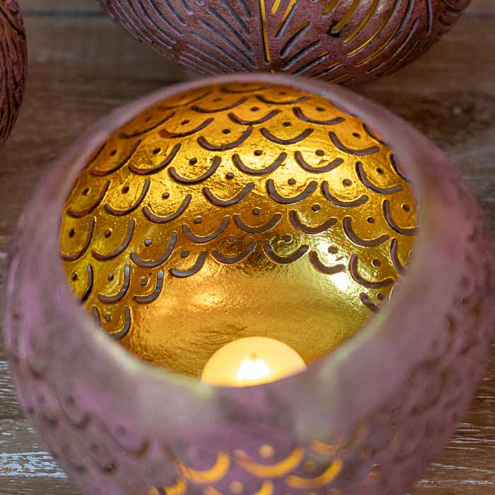 Detalhe da luz vazando pelos entalhes artesanais de porta-vela balinês.