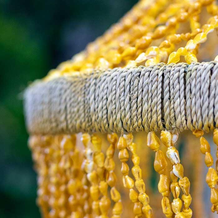 Ornamento boho de teto com conchas sobrepostas, trazendo leveza e textura ao lar.