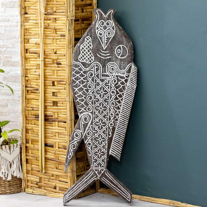 Painel entalhado à mão em madeira com forma de peixe, inspirado na arte tribal de Timor.