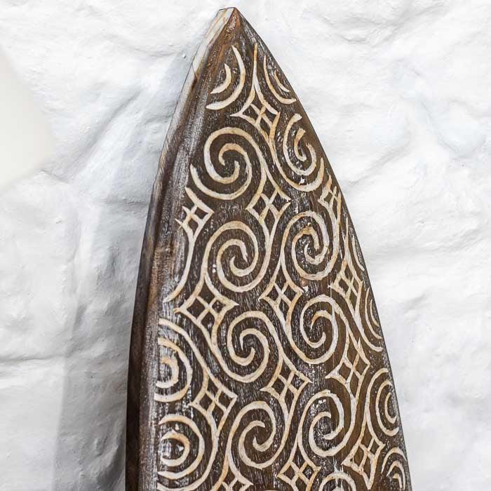 Objeto decorativo timorense em madeira entalhada à mão com símbolos ancestrais, representando a harmonia entre tradição e arte artesanal.