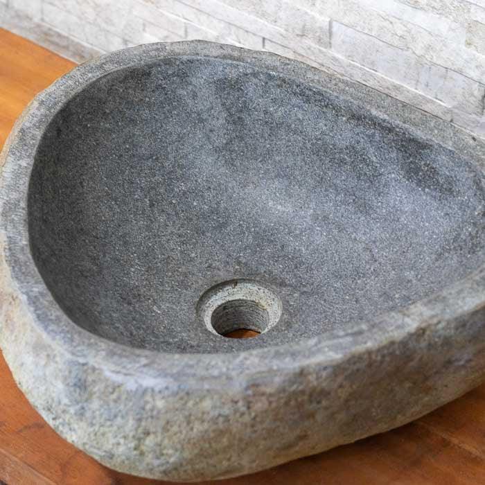 Pia artesanal balinesa feita em bloco de pedra, valorizando a estética da natureza bruta.