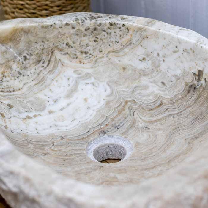 Detalhe da borda rústica da Cuba de pedra natural, contrastando com o interior liso.