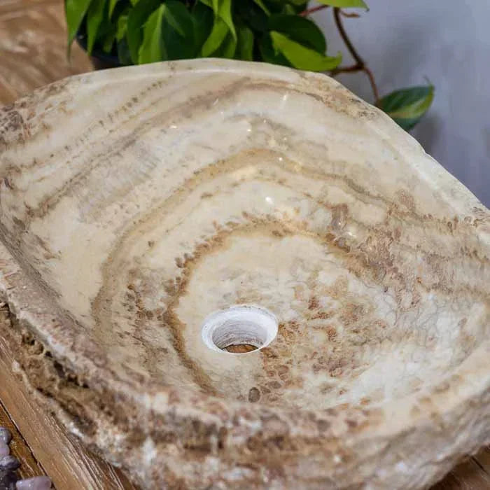 Pia de lavabo esculpida à mão em Bali, com interior polido e camadas minerais visíveis.