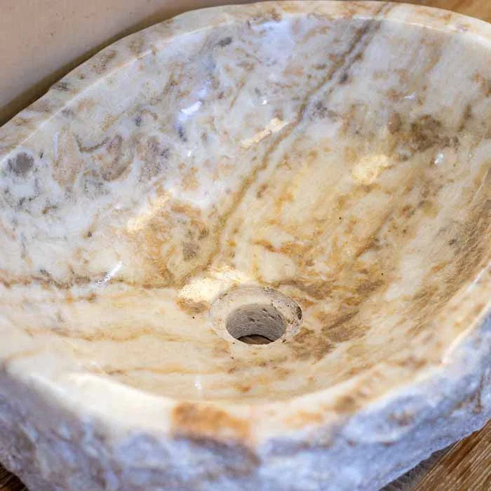 Pia de lavabo esculpida à mão em Bali, com interior polido e camadas minerais visíveis.