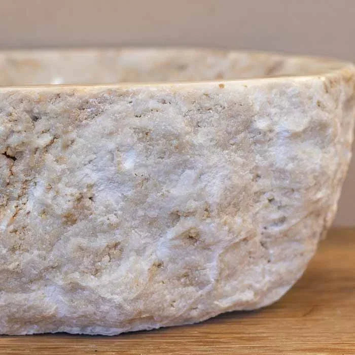 Pia de lavabo esculpida à mão em Bali, com interior polido e camadas minerais visíveis.