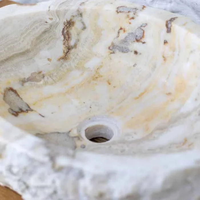 Pia de lavabo esculpida à mão em Bali, com interior polido e camadas minerais visíveis.