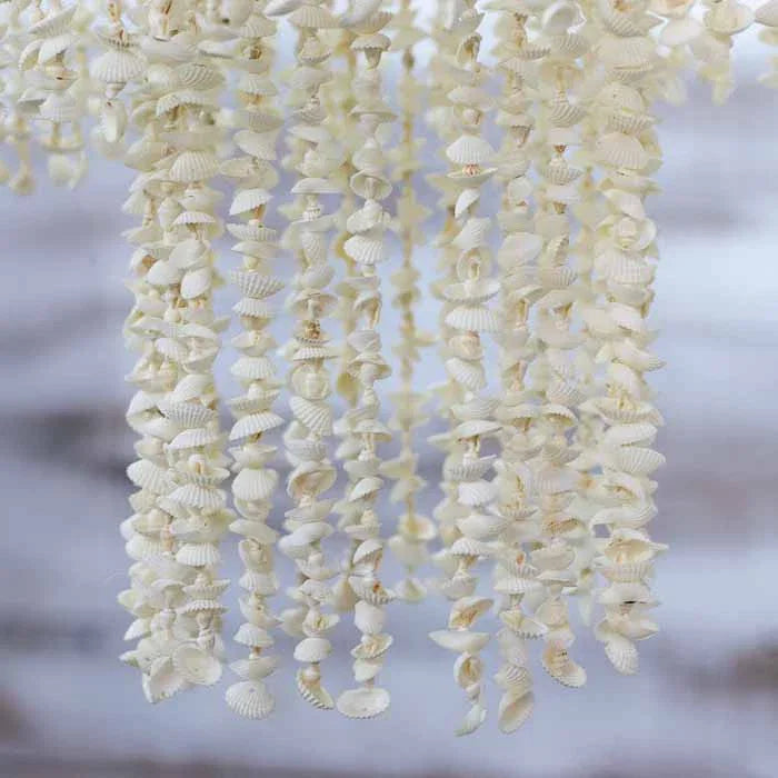 Detalhe das fileiras de conchas naturais em lustre pendente de estilo litorâneo.