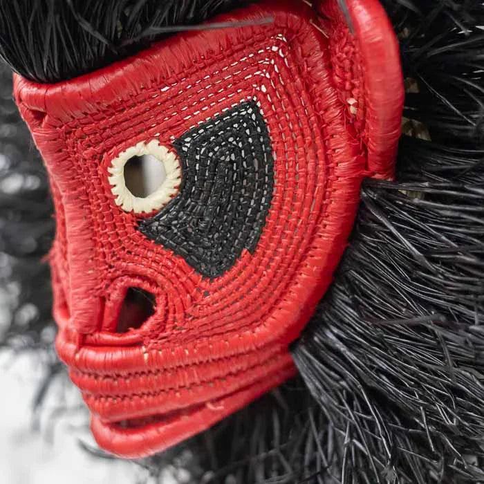 Detalhe da trama artesanal em máscara étnica de macaco nas cores marrom e preto.