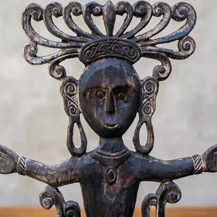 Detalhe do rosto estilizado e texturas rústicas em totem de madeira da Indonésia.