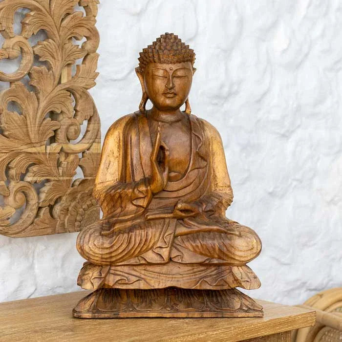 Arte balinesa em madeira com Buda em postura meditativa e serena.