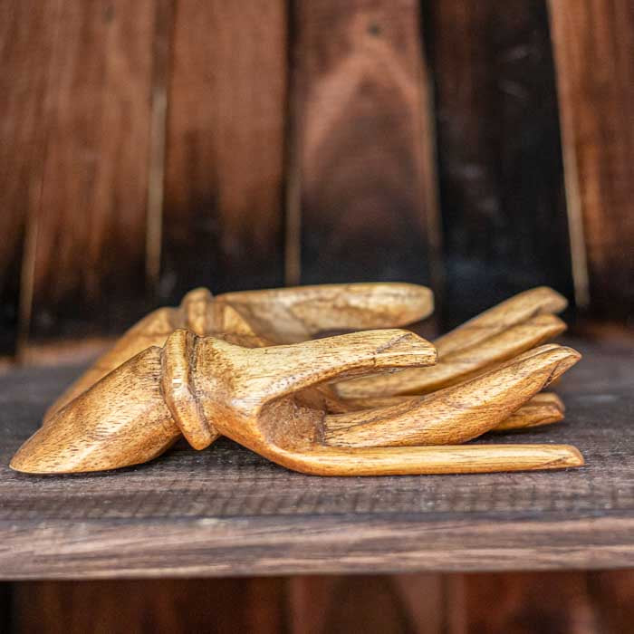 Objeto de madeira balinês com formato de mãos entrelaçadas artesanais.