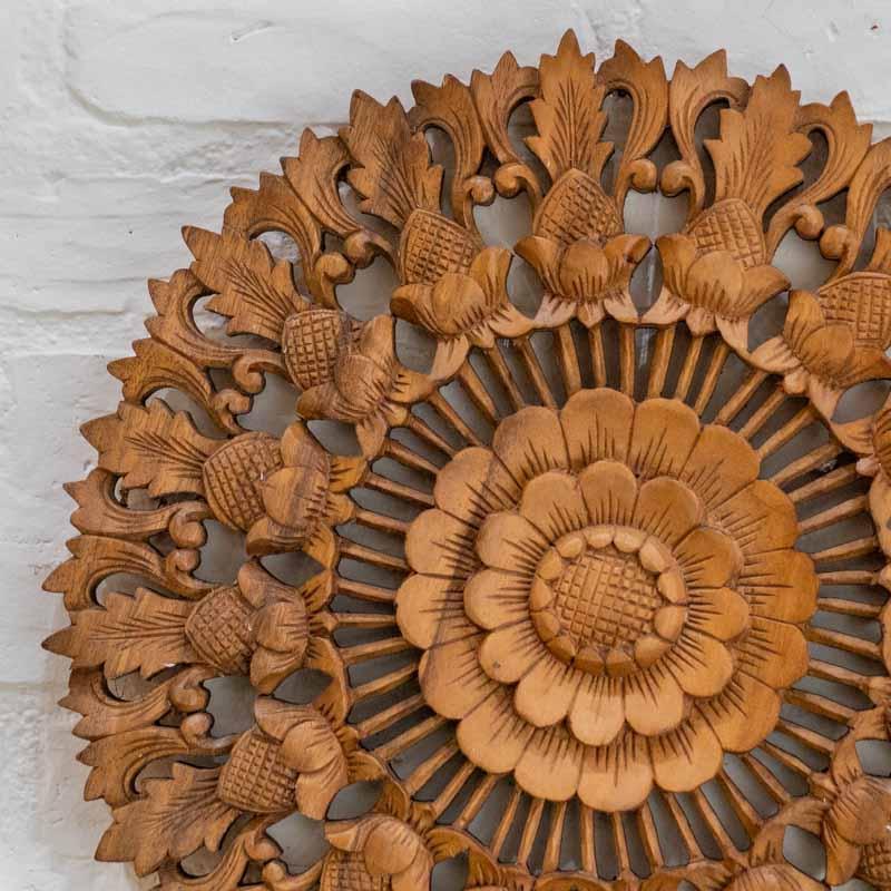 Detalhe do padrão botânico e textura natural em mandala artesanal de madeira clara.