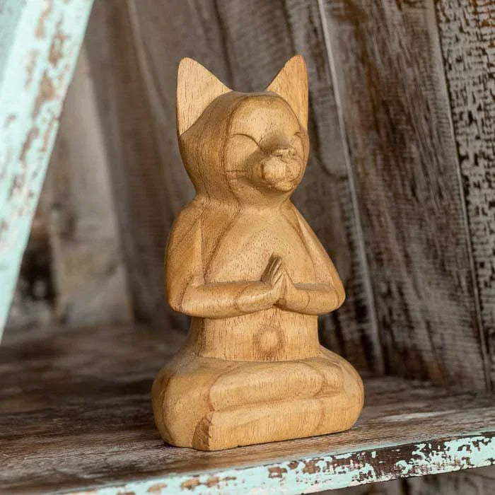 Peça espiritual balinesa representando gato em posição de prece.
