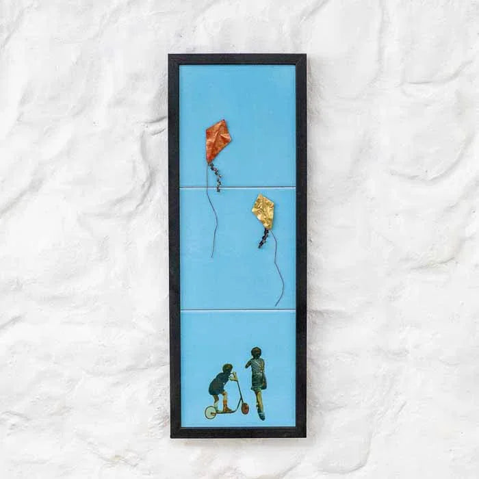 Quadro artesanal 3D com tema de pipas coloridas e rabiolas sobre fundo azul claro.
