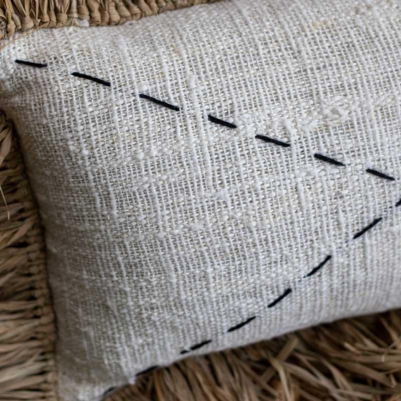 Almofada boho estilo artesanal em fibra natural bordada com traços.