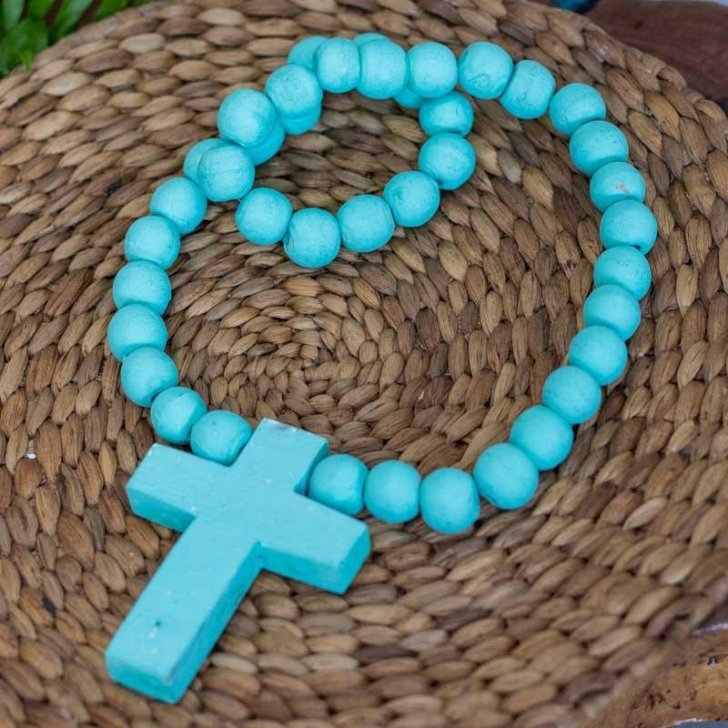 Detalhe da cruz de madeira rústica e contas esféricas em adorno espiritual importado de Bali.