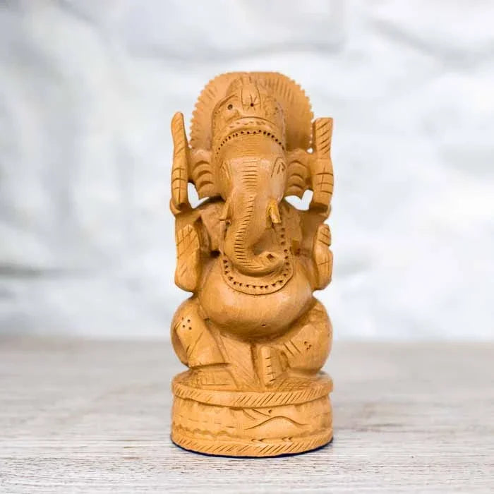 Esculturas de Ganesha em madeira clara entalhada alinhadas por variação de tamanho.