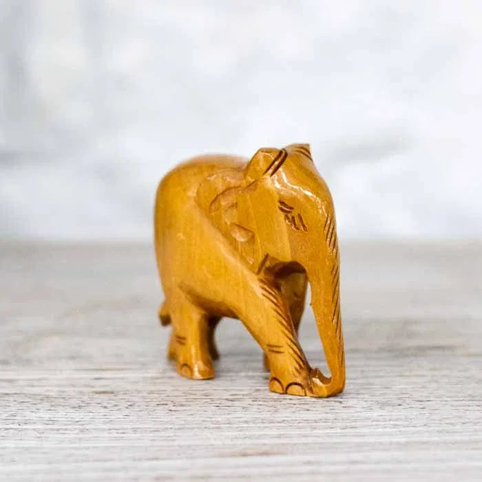Detalhe da escultura de elefante indiano com a trompa voltada para baixo e orelhas entalhadas.