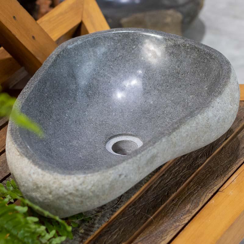 Detalhe da pia em pedra natural esculpida à mão, integrando design biofílico e luxo rústico ao banheiro.