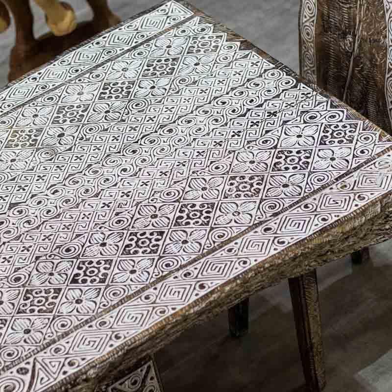 Detalhe superior do tampo de madeira sólida com mandalas e grafismos timorenses preenchidos com pátina branca.
