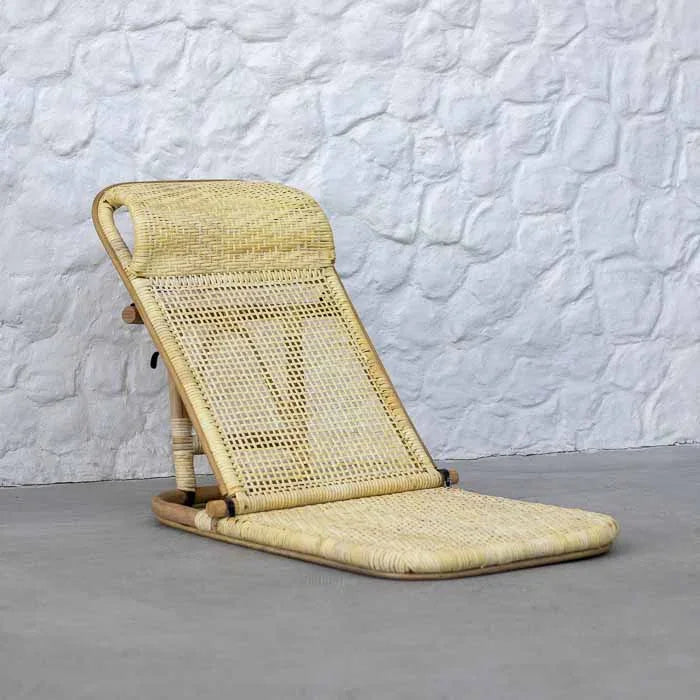 Cadeira de descanso portátil em rattan claro ideal para leitura e relaxamento próximo ao solo.