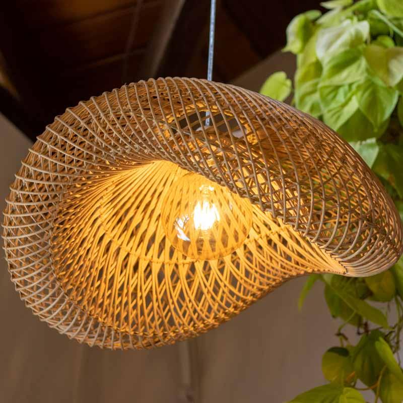 Luminária Peyoc iluminada destacando a textura da fibra natural e as sombras projetadas no ambiente.