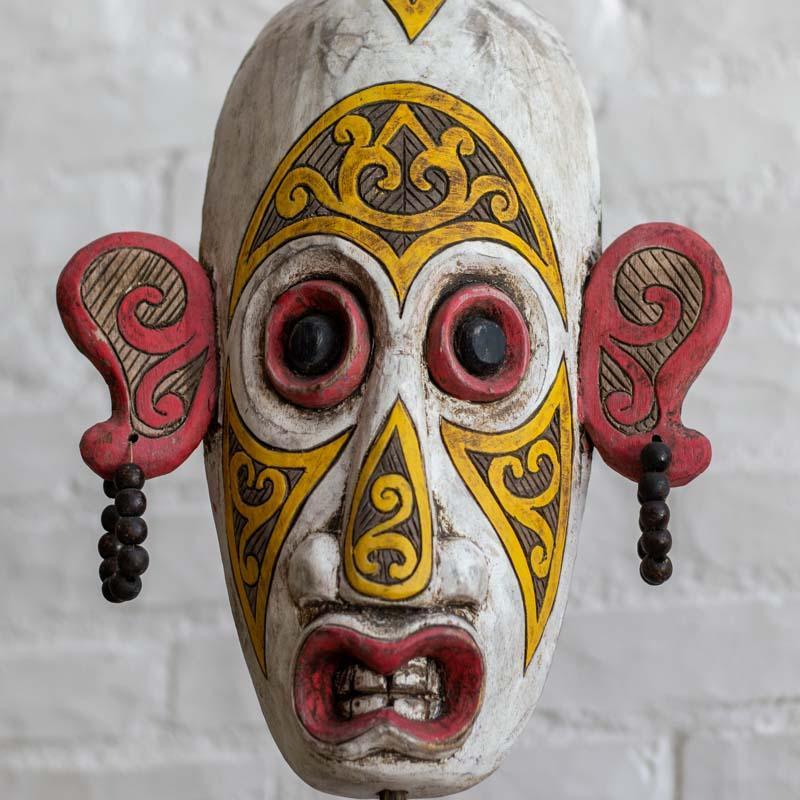 Design original da Indonésia: máscara que harmoniza a força do entalhe primitivo com a estética decorativa moderna.