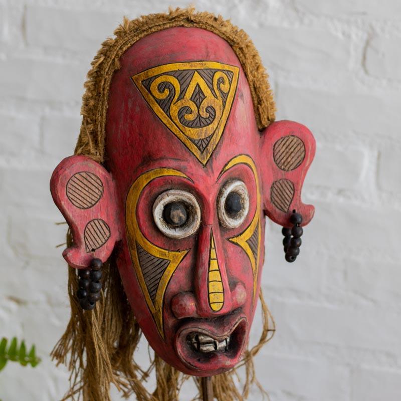 Escultura de madeira com pátina colorida e traços primitivos, peça exclusiva de Bornéu para decoração de interiores.
