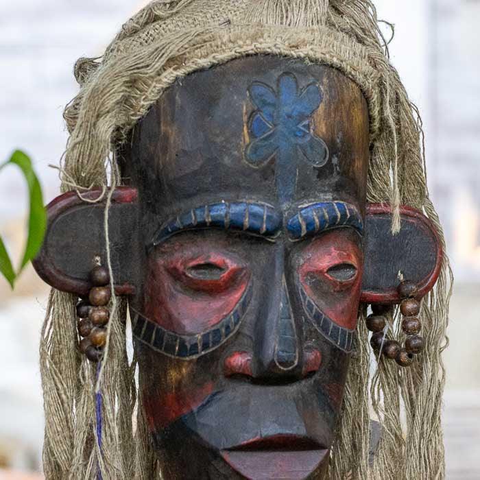 Escultura decorativa tribal de Bornéu entalhada em madeira com adornos de fibras naturais, representando a arte e espiritualidade das ilhas indonésias.