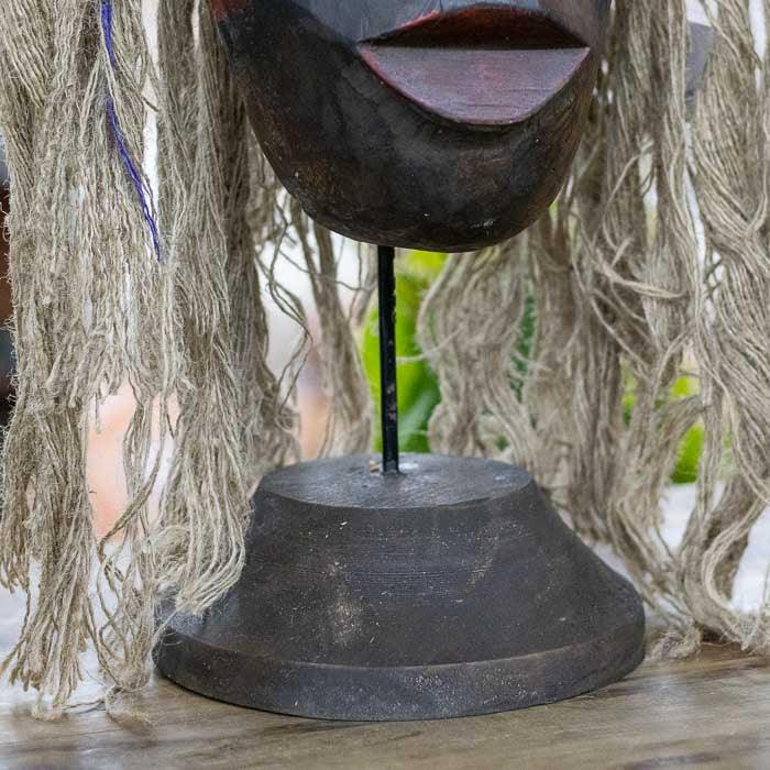 Máscara artesanal em madeira com cabelos de fibra natural e traços pintados à mão, expressão cultural e simbólica das tribos de Bornéu.