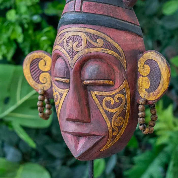 Máscara artesanal com entalhes profundos e expressão simbólica kekuatan