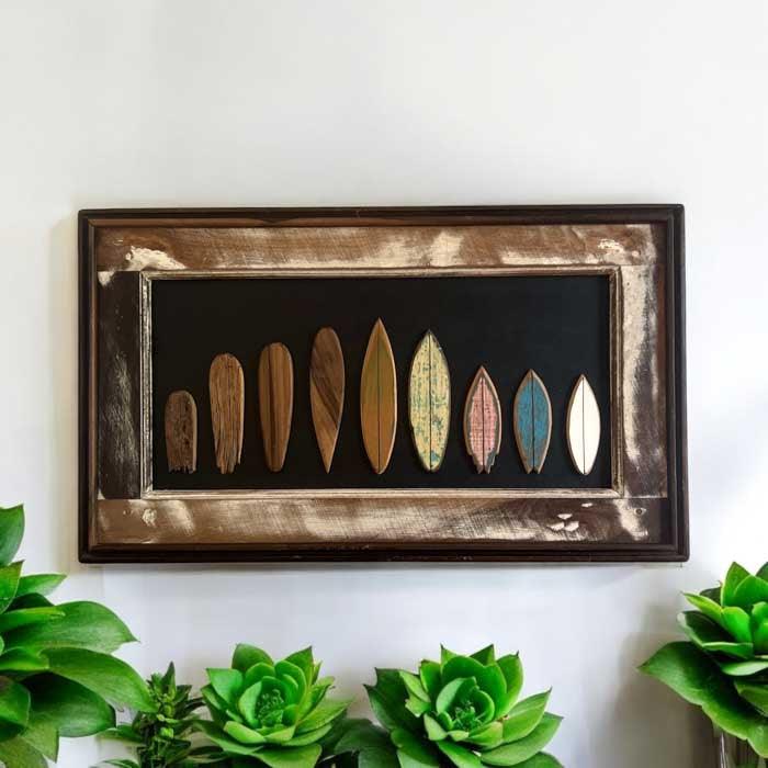 Detalhe da moldura rústica em madeira de demolição e evolução dos shapes de surf em quadro exclusivo de artista brasileiro.