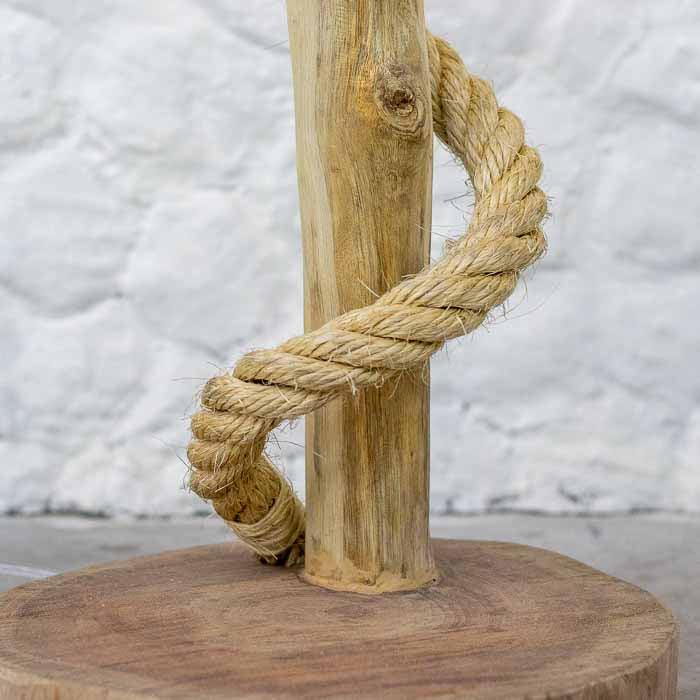 Pedestal de iluminação cênica feito de galho natural com bocal pendente e lâmpada filamentada acesa.