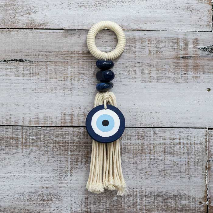 Protetor de porta em algodão cru com pedras naturais e amuleto azul.