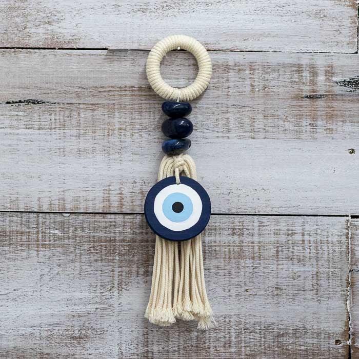 Protetor de porta em algodão cru com pedras naturais e amuleto azul.