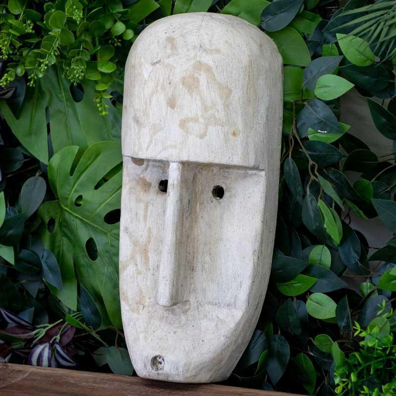 Escultura de parede artesanal de Timor exibindo traços lineares e furos circulares nos olhos.