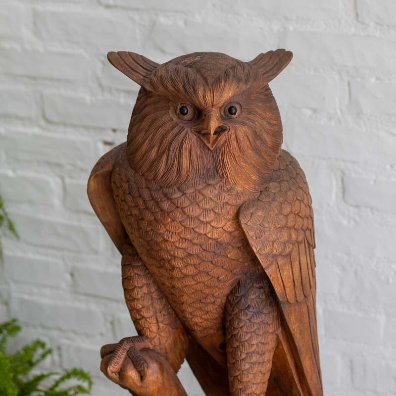 Decoração inspirada na fauna asiática com estátua de coruja em tons de madeira natural.