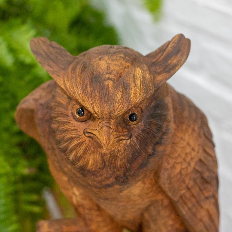 Detalhe do trabalho artesanal indonésio destacando as penas e os olhos da coruja em madeira.