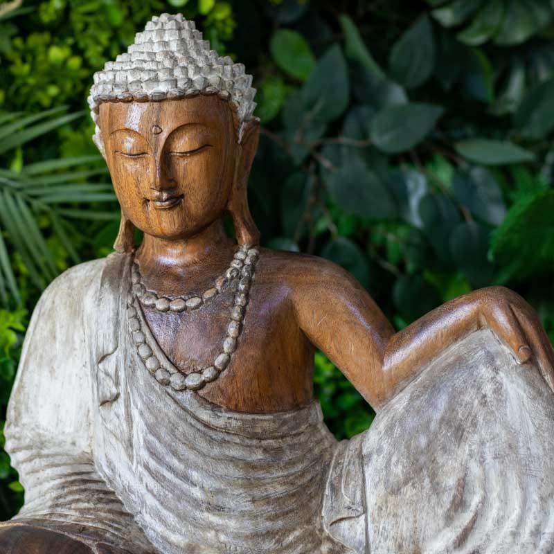 Detalhe da face serena de Buda entalhado à mão em madeira natural, destacando o coque tradicional e a expressão de paz absoluta.