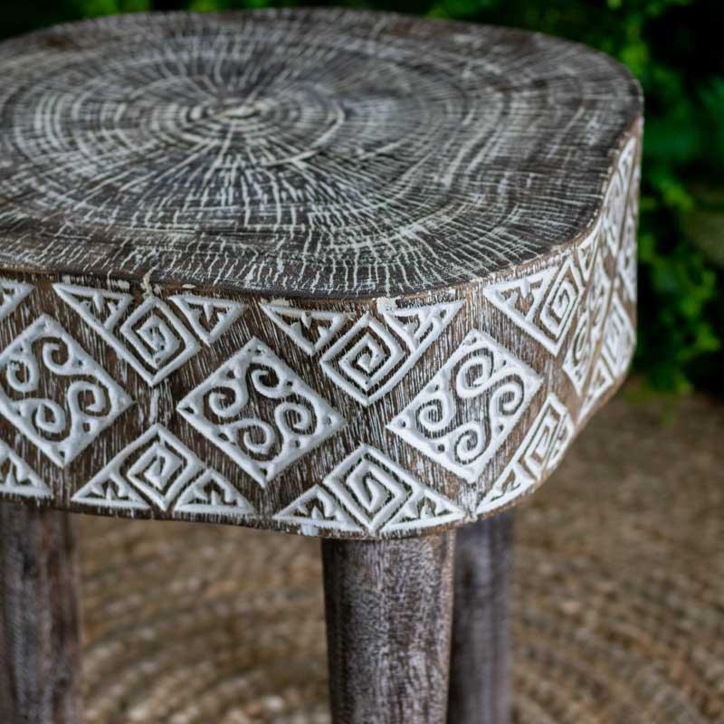 Mesa de canto artesanal em madeira maciça de Timor com entalhes tribais geométricos e acabamento em pátina branca.