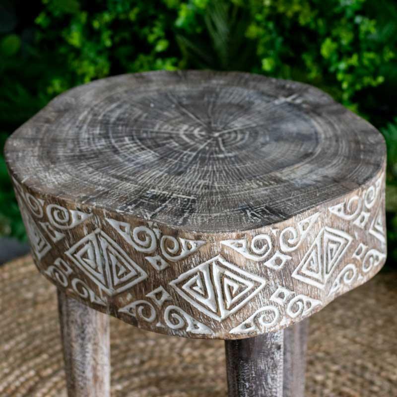 Mesa de canto tribal posicionada sobre tapete de fibra natural, criando uma composição de design orgânico e acolhedor.