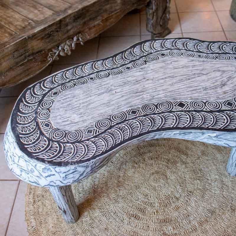 Detalhe superior do tampo de mesa entalhada à mão com grafismos de espirais e padrões étnicos da Indonésia.