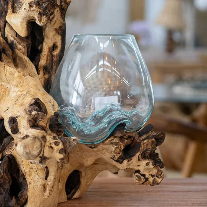 Detalhe do vaso de vidro soprado artesanal em tronco de madeira balinesa, revelando o processo natural de moldagem e o equilíbrio entre transparência e rusticidade.