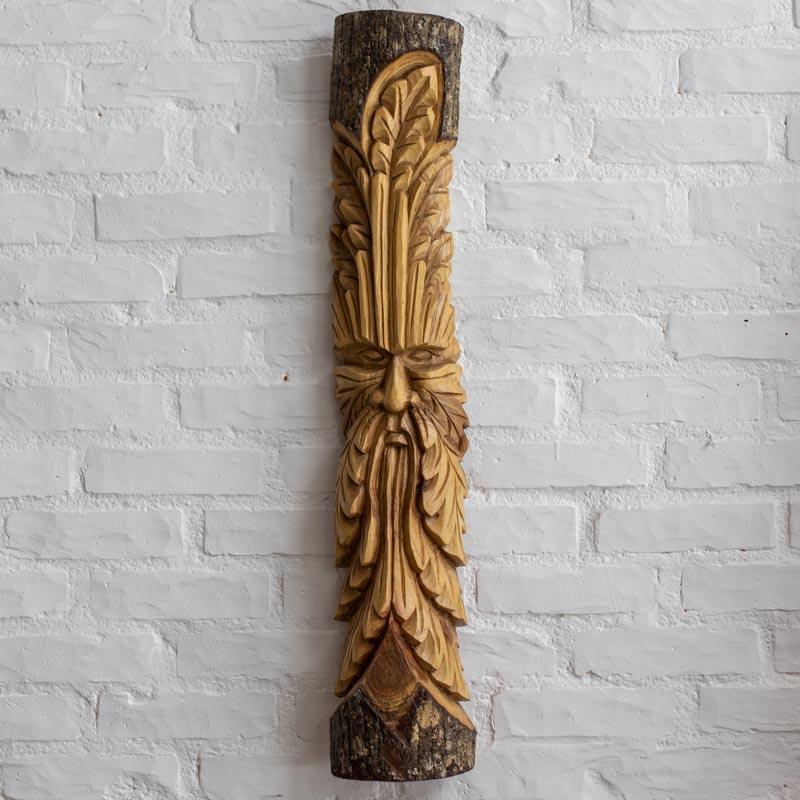 Escultura no tronco com entalhe detalhado do rosto ancestral Green Man.