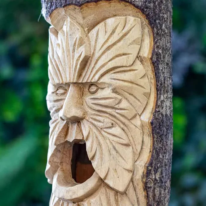 Escultura GreenMan em tronco usada como casa de passarinho decorativa.