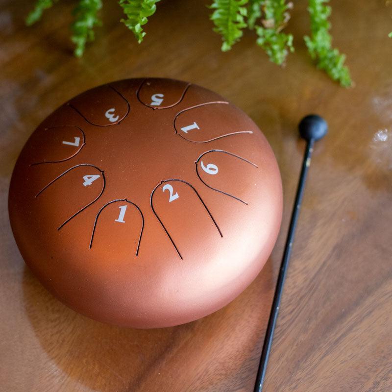 Detalhe superior de tambor de língua em metal com cortes precisos que definem as notas musicais para práticas de meditação.