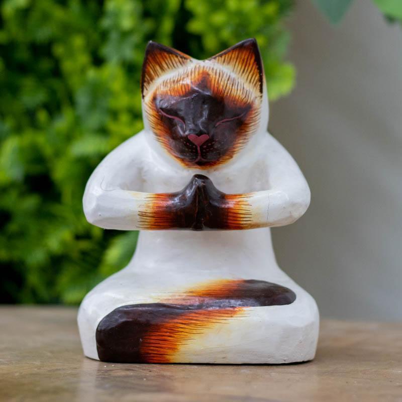 Escultura artesanal de gato em madeira de Bali, retratado em postura sentada com as patas unidas no gesto sagrado de Anjali Mudra.