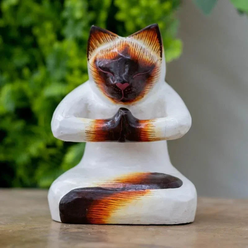 Escultura artesanal de gato em madeira de Bali, retratado em postura sentada com as patas unidas no gesto sagrado de Anjali Mudra.