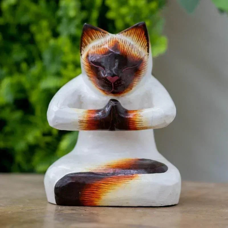 Escultura artesanal de gato em madeira de Bali, retratado em postura sentada com as patas unidas no gesto sagrado de Anjali Mudra.
