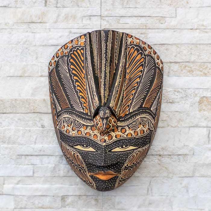 Máscara artesanal de Bali esculpida em madeira com pintura na técnica Batik, destacando padrões culturais indonésios
